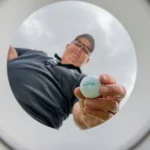 Golfer shows golf ball from cup perspective